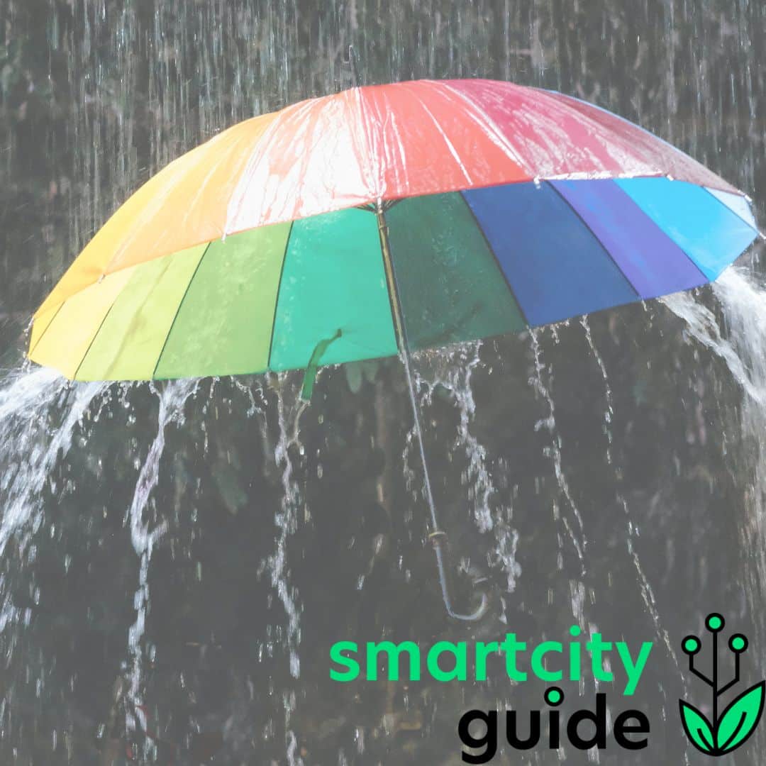 Regenschirm in Regenbogenfarben schützt vor starkem Regen. Unten rechts das "smartcity guide"-Logo.
