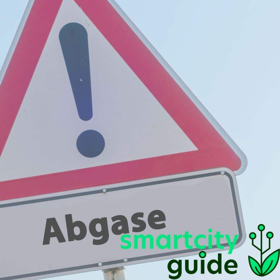 Verkehrsschild mit Ausrufezeichen und "Abgase" Beschriftung auf hellem Hintergrund, Smart City Guide Logo